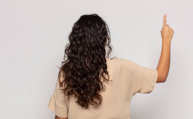 Güzel genç bir kadın dikiz aynasındaki nesneyi işaret ediyor.