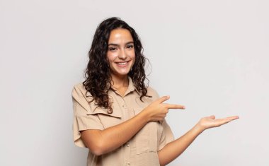 Güzel genç bir kadın gülümsüyor, mutlu, kaygısız ve tatmin olmuş hissediyor, fotokopi alanındaki konsepte ya da fikre işaret ediyor.