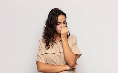 Güzel genç bir kadın ciddi, düşünceli ve endişeli, elleri çenesine bastırılmış, yan bakıyor.