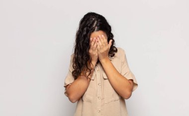 Güzel genç bir kadın üzgün, hayal kırıklığına uğramış, gergin ve depresif hissediyor. İki eliyle yüzünü kapatıyor, ağlıyor.