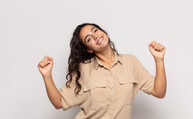 Güzel genç bir kadın son derece mutlu ve şaşırmış görünüyor, başarıyı kutluyor, bağırıyor ve zıplıyor.