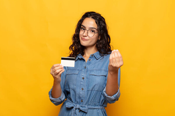 молодая испаноязычная женщина делает капис или денежный жест, говоря вам, чтобы оплатить ваши долги!