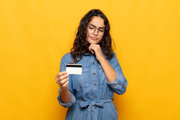 молодая латиноамериканка думает, чувствуя сомнение и замешательство, с различными вариантами, задаваясь вопросом, какое решение принять