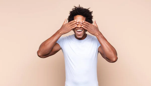 Mladý Černý Afro Muž Zakrývající Tvář Rukama Vykukující Mezi Prsty — Stock fotografie