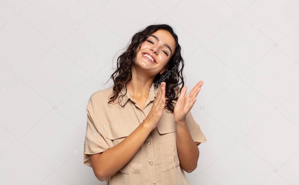 pretty young woman feeling happy and successful, smiling and clapping hands, saying congratulations with an applause