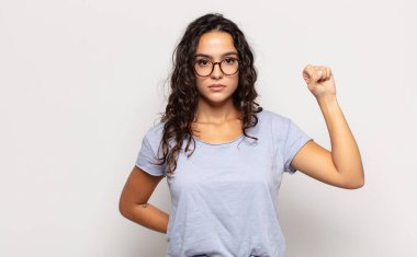 Güzel genç bir kadın ciddi, güçlü ve asi hissediyor, yumruğunu kaldırıyor, protesto ediyor ya da devrim için savaşıyor.