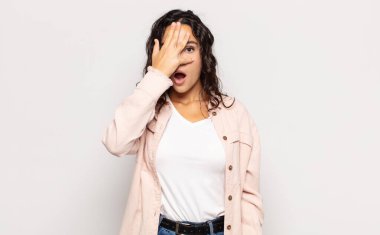 Güzel, genç bir kadın şok olmuş, korkmuş ya da korkmuş görünüyor. Yüzü elle kaplanmış ve parmaklarının arasından gizlice bakıyor.