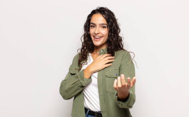 Güzel genç bir kadın mutlu ve aşık, bir eli kalbinin yanında gülümsüyor ve diğer eli önde uzanıyor.