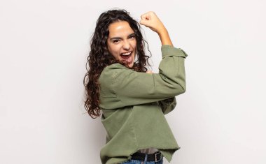 Güzel genç bir kadın kendini mutlu, tatmin olmuş ve güçlü hissediyor, kaslı ve formda, spor salonundan sonra güçlü görünüyor.