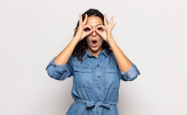 Güzel genç bir kadın şaşkın, şaşırmış ve şaşırmış hissediyor. Elinde şaşkın, inançsız bir bakışla gözlük tutuyor.