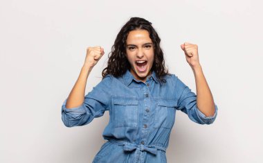 Güzel genç bir kadın öfkeli bir ifadeyle ya da yumruklarıyla başarıyı kutlarken agresif bir şekilde bağırıyor.