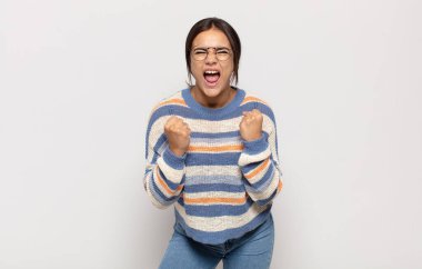 Güzel genç bir kadın sinirli, sinirli, kızgın bakışlar ve sıkı yumruklar ile agresif bir şekilde bağırıyor.