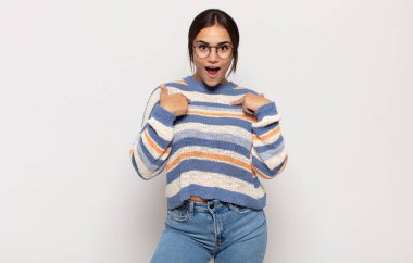 Güzel genç bir kadın mutlu, şaşkın ve gururlu hissediyor, heyecanlı ve şaşkın bir bakışla kendini işaret ediyor.