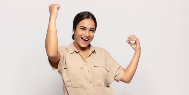 Güzel genç bir kadın muzaffer bir şekilde bağırıyor. Heyecanlı, mutlu ve şaşırmış görünüyor. Kutlama yapıyor.