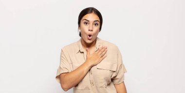 Güzel genç bir kadın şok olmuş ve şaşırmış hissediyor, gülümsüyor, el ele tutuşuyor, o olmaktan mutlu ya da minnettarlık gösteriyor.