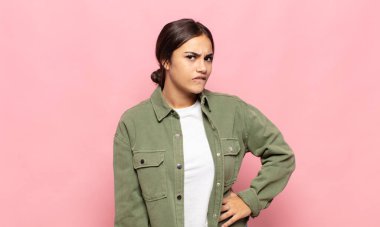 Güzel genç bir kadın şüphe ediyor ya da düşünüyor, dudağını ısırıyor ve kendini güvensiz ve gergin hissediyor, kenarda yer arıyor.