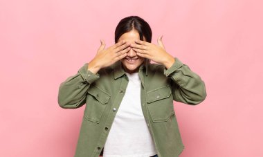 Güzel genç bir kadın gülümsüyor ve mutlu hissediyor, iki eliyle gözlerini kapatıyor ve inanılmaz bir sürpriz bekliyor.