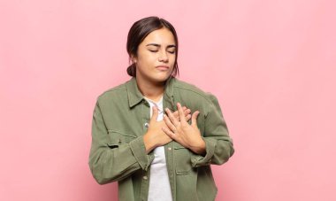 Güzel genç bir kadın üzgün, yaralı ve kalbi kırık görünüyor, iki elini de kalbe yakın tutuyor, ağlıyor ve bunalımda.