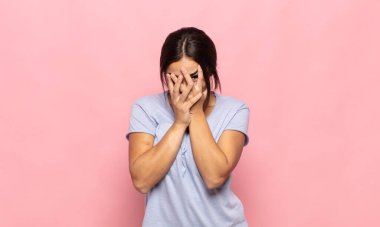 Güzel genç bir kadın korkmuş ya da utanmış hissediyor. Gözleri yarı kapalı ya da ellerle dikizliyor ya da dikizliyor.