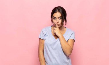 Güzel genç bir kadın sessizlik ve sessizlik istiyor, parmaklarıyla ağzının önünde işaret ediyor, 