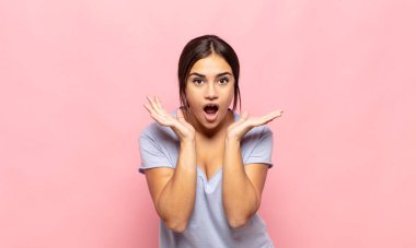 Güzel genç bir kadın beklenmedik bir sürpriz yüzünden şaşkın, heyecanlı, gülen, şaşkın ve mutlu hissediyor.