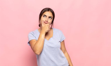 Düşünen, kuşkulu ve kafası karışık, farklı seçenekleri olan, hangi kararı vereceğini merak eden genç bir kadın.