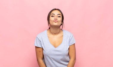 Güzel, genç bir kadın dudaklarını birbirine bastırıyor. Sevimli, eğlenceli, mutlu, sevimli bir yüz ifadesiyle. Öpücük gönderiyor.