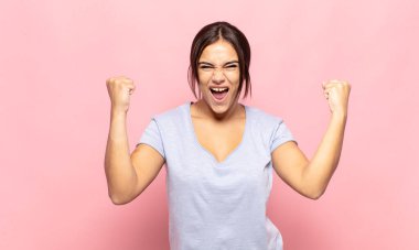 Güzel genç bir kadın öfkeli bir ifadeyle ya da yumruklarıyla başarıyı kutlarken agresif bir şekilde bağırıyor.