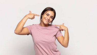 Güzel, genç bir kadın, kendine güvenerek gülümsüyor. Kendi gülüşünü gösteriyor. Olumlu, rahat, tatmin olmuş bir tavır.