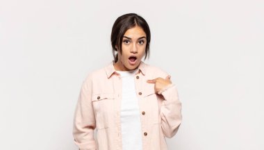 Şok olmuş ve ağzı açık, kendini işaret eden güzel genç bir kadın.