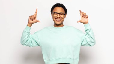 Genç afro kadın kendi gülüşünü çiziyor, iki eliyle, pozitif ve mutlu görünüyor, sağIık kavramı