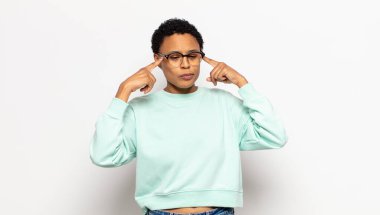 Genç afro kadın konsantre olmuş ve bir fikir üzerinde kafa yoruyor, bir soruna ya da soruna bir çözüm hayal ediyor.