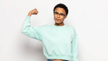 Genç afro kadın kendini mutlu, tatmin olmuş ve güçlü hissediyor, kaslı ve formda, spor salonundan sonra güçlü görünüyor.