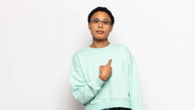 Genç afro kadın şaşkın, şaşkın ve güvensiz hissediyor, kendini gösterip kim olduğunu soruyor, ben mi??