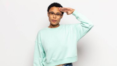 Genç afro kadın kameraya askeri bir selamlama ile saygı göstererek, onur ve vatanseverlik göstererek selam veriyor.