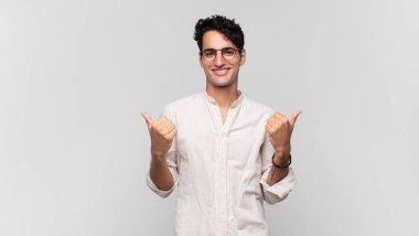 Genç ve yakışıklı adam neşeyle gülümsüyor ve mutlu görünüyor, kaygısız ve pozitif hissediyor.