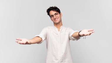 Genç yakışıklı adam neşeyle gülümsüyor sıcak, dostça, sevgi dolu bir kucak veriyor, mutlu ve sevimli hissediyor.