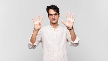 Genç yakışıklı adam gülümsüyor ve arkadaş canlısı görünüyor. 9 ya da 9 numarayı gösteriyor. Elleri önde, geriye doğru sayıyor.