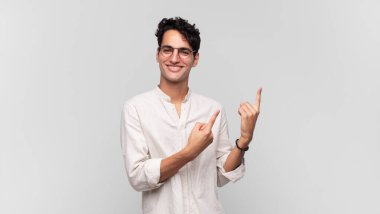 Genç yakışıklı adam mutlu bir şekilde gülümsüyor ve her iki elinde fotokopi alanında nesne gösteriyor.