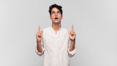 Genç yakışıklı adam şaşırmış, şaşırmış ve ağzı açık, iki eliyle uzayı göstererek