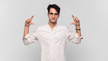 Genç yakışıklı bir adam kendi gülüşünü çiziyor ya da özetliyor iki eliyle, pozitif ve mutlu görünüyor, sağIık kavramı.