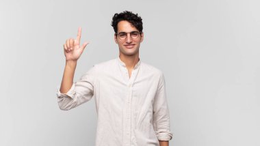 Genç yakışıklı adam neşeyle ve mutlulukla gülümsüyor, tek eliyle yukarıyı göstererek boşluğu kopyalıyor.