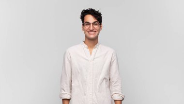 Genç yakışıklı adam mutlu ve şapşal görünüyor. Geniş, eğlenceli, kaçık bir gülüşü ve açık gözleri var.