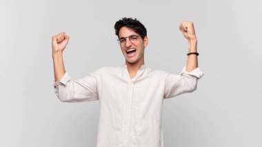 Genç yakışıklı adam zaferle bağırıyor. Heyecanlı, mutlu ve şaşırmış görünüyor. Kutlama yapıyor.