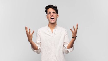 Genç yakışıklı adam öfkeyle bağırıyor, stresli hissediyor ve ellerini havaya kaldırıp neden ben diye bağırıyor.