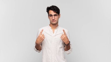 Kötü tavırlı genç yakışıklı adam gururlu ve agresif görünüyor, yukarıyı işaret ediyor ya da elleriyle alay işareti yapıyor.