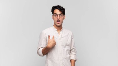 Şok olmuş ve ağzı açık, kendini işaret eden genç yakışıklı bir adam.