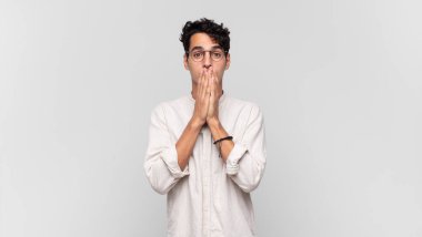 Genç yakışıklı adam mutlu ve heyecanlı, şaşırmış ve şaşırmış elleri ağızda, tatlı bir ifadeyle kıkırdıyor.