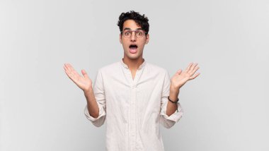 Genç yakışıklı adam mutlu ve heyecanlı görünüyor. Beklenmedik bir sürprizle şoke olmuş. İki eli yüzü açık.