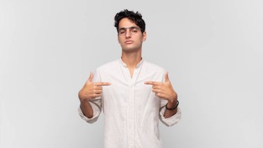 Genç yakışıklı adam gururlu, pozitif ve iki eliyle göğsünü gösteren